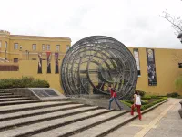 Miguel et Marie devant le palais gouvernemental et une oeuvre d'art renfermant une oeuvre pré-colombienne : roche taillée en une boule parfaite.